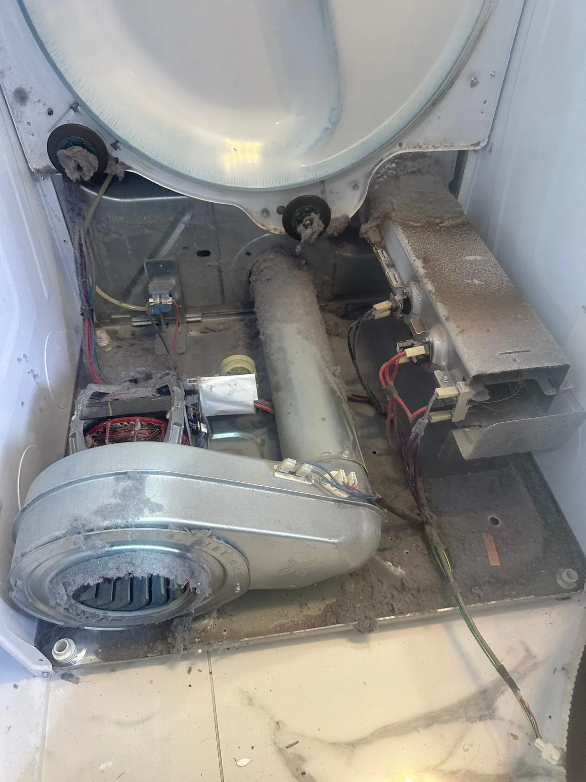 Dryer interior caked in heavy lint and dust buildup before deep cleaning