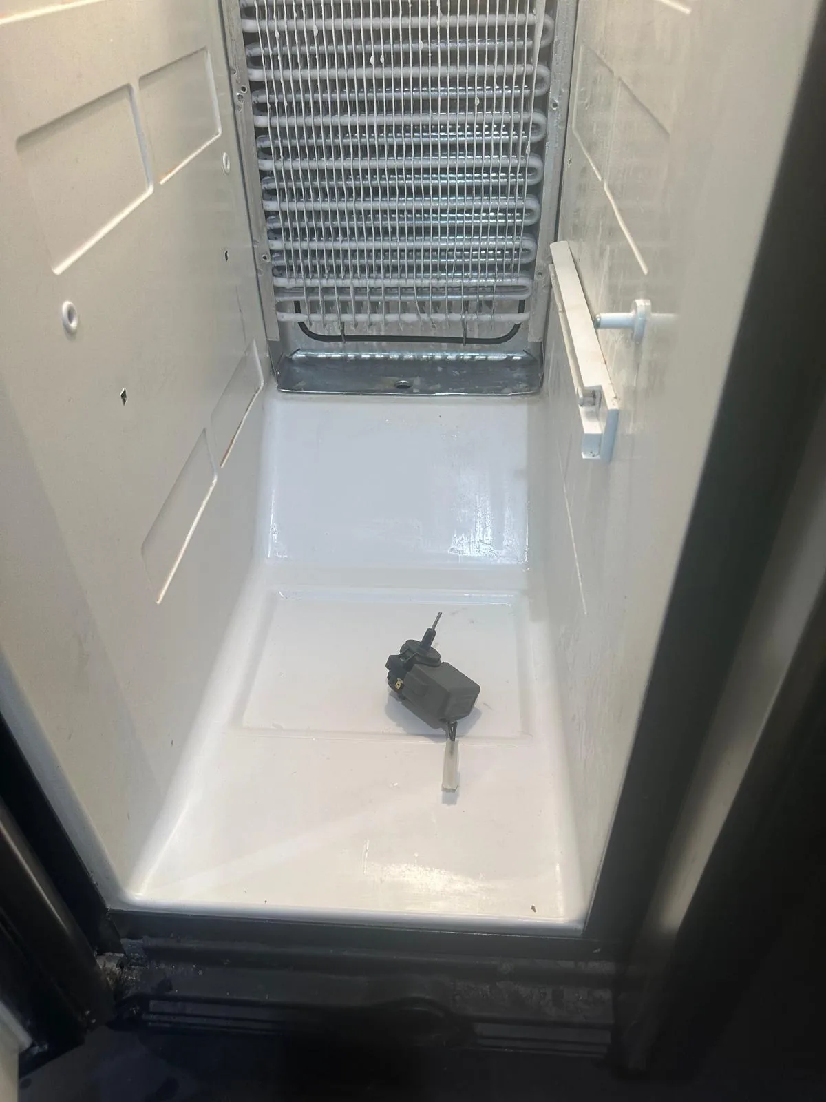 Failed evaporator fan motor removed from GE refrigerator freezer compartment