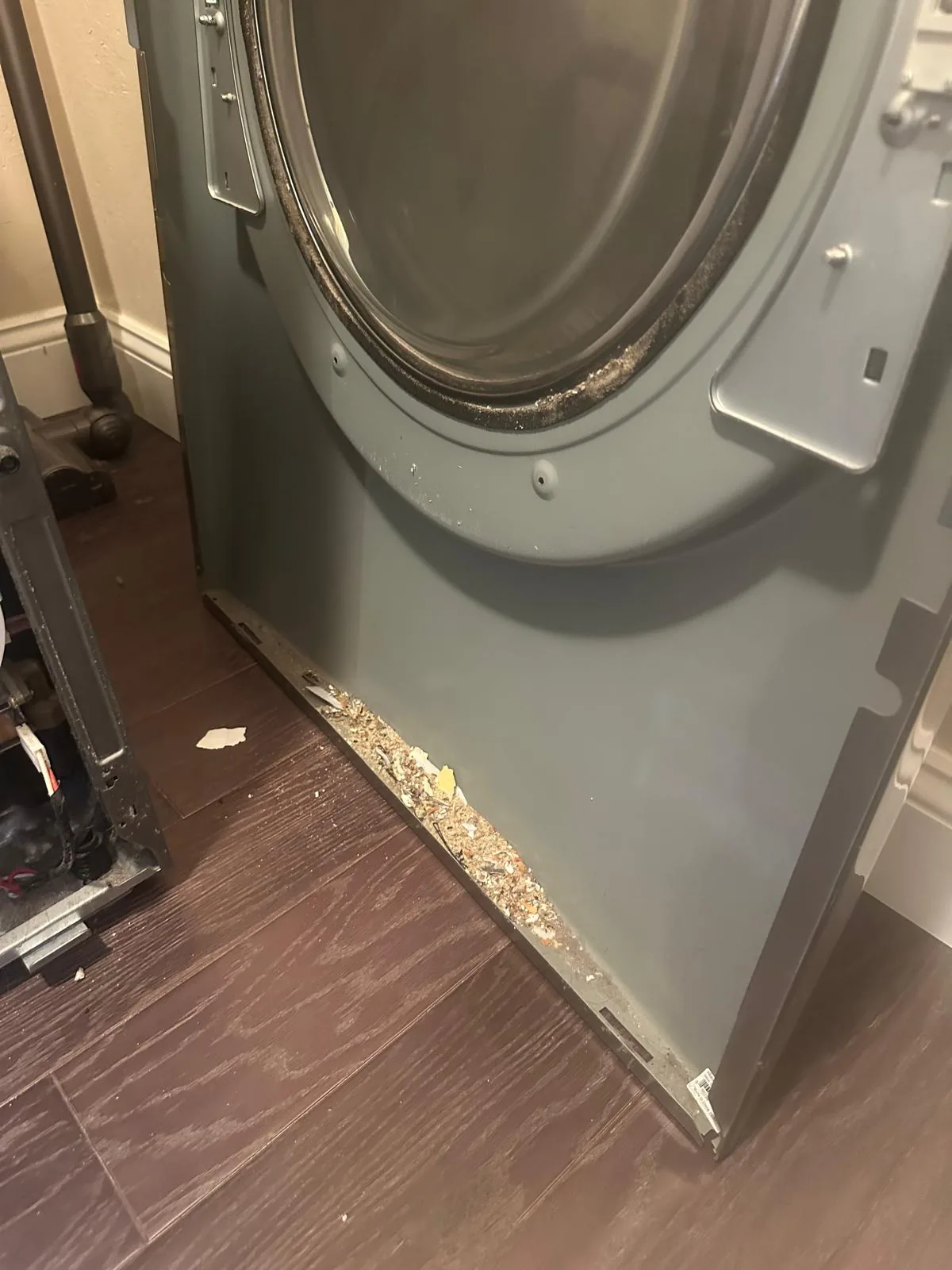 LG dryer front panel removed with lint and debris buildup along the bottom edge during the repair